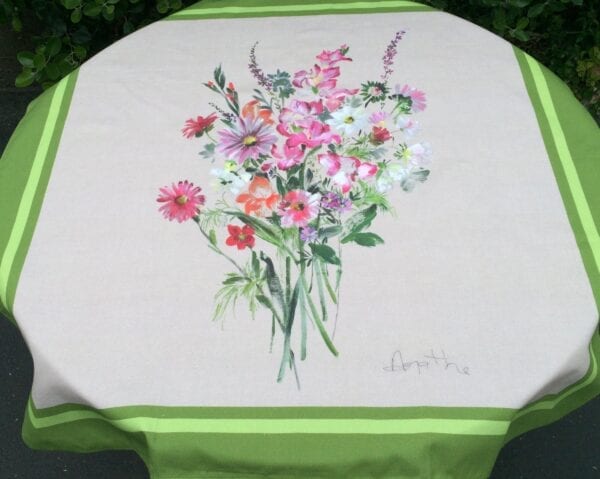 A white table cloth bordered in green with flowers in the center