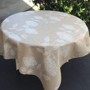 A parchment colored linen table cloth with white flower patterns