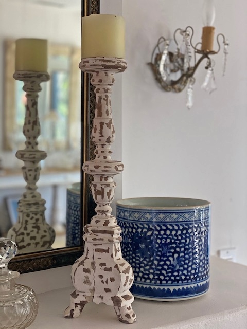 A white candlestand in front of a mirror