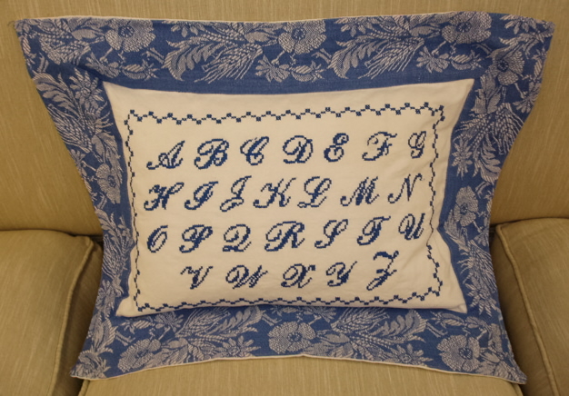 A blue pillow case with the alphabet design
