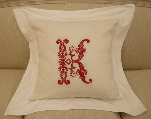 A white pillow case with a red K embroided in it
