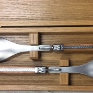 Two metal utensils with cream handles in a box
