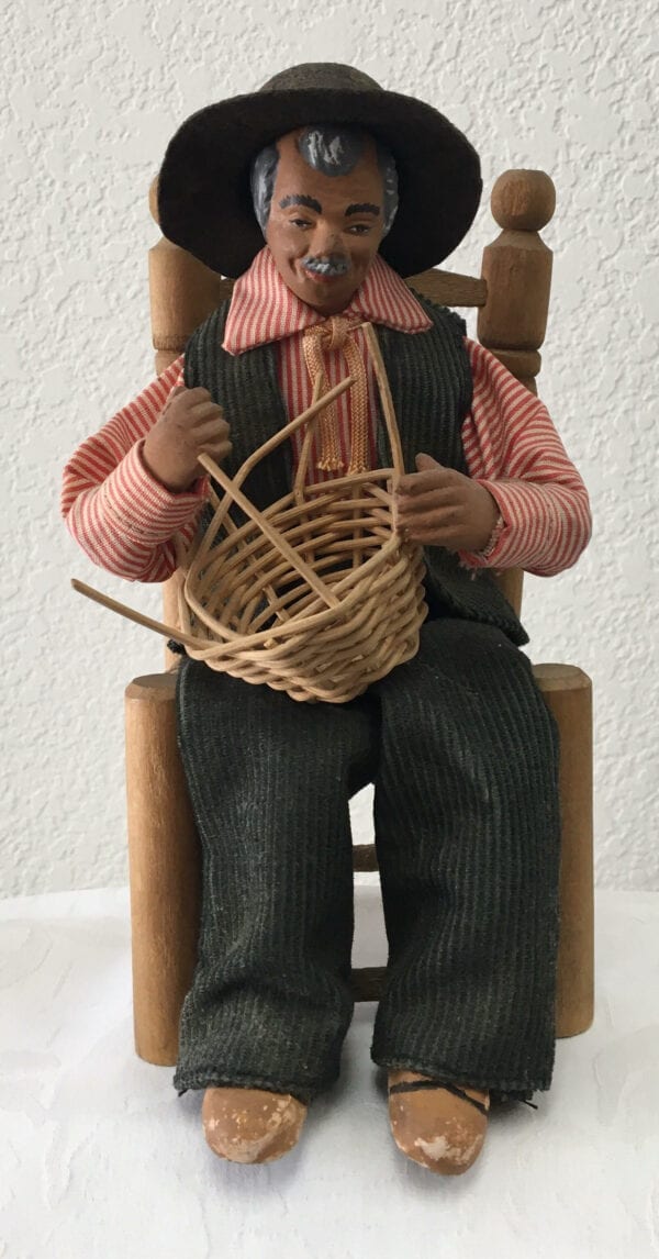 A small statue of an old man weaving a basket