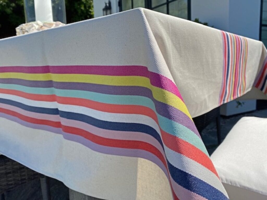 A white table cloth with pale colorful stripes at the sides and center