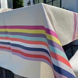 A white table cloth with pale colorful stripes at the sides and center