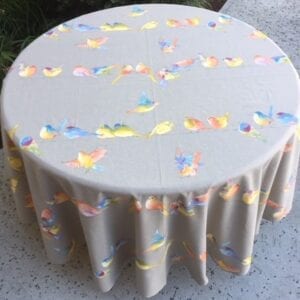 A grey table cloth with colorful bird designs