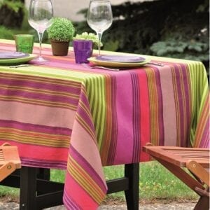 A pink and green table cloth with dishes and glasses